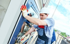 builders worker installing glass windows on facade