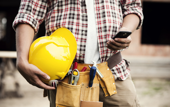 Close-up of construction worker texting on mobile phone
