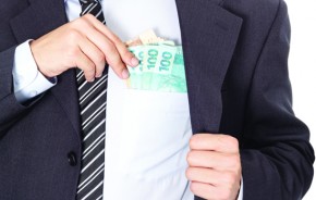 A businessman in a suit putting money in his pocket